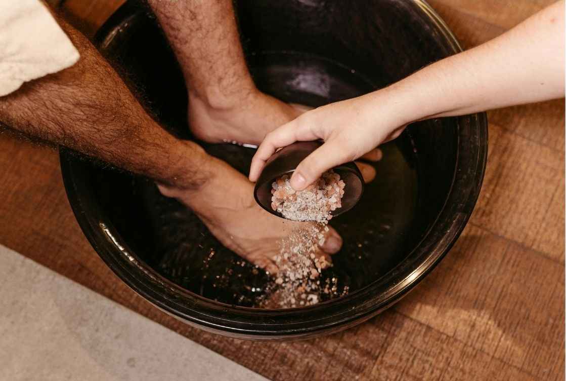 2 Männerfüße in Fußbecken bei Zugabe von Salz